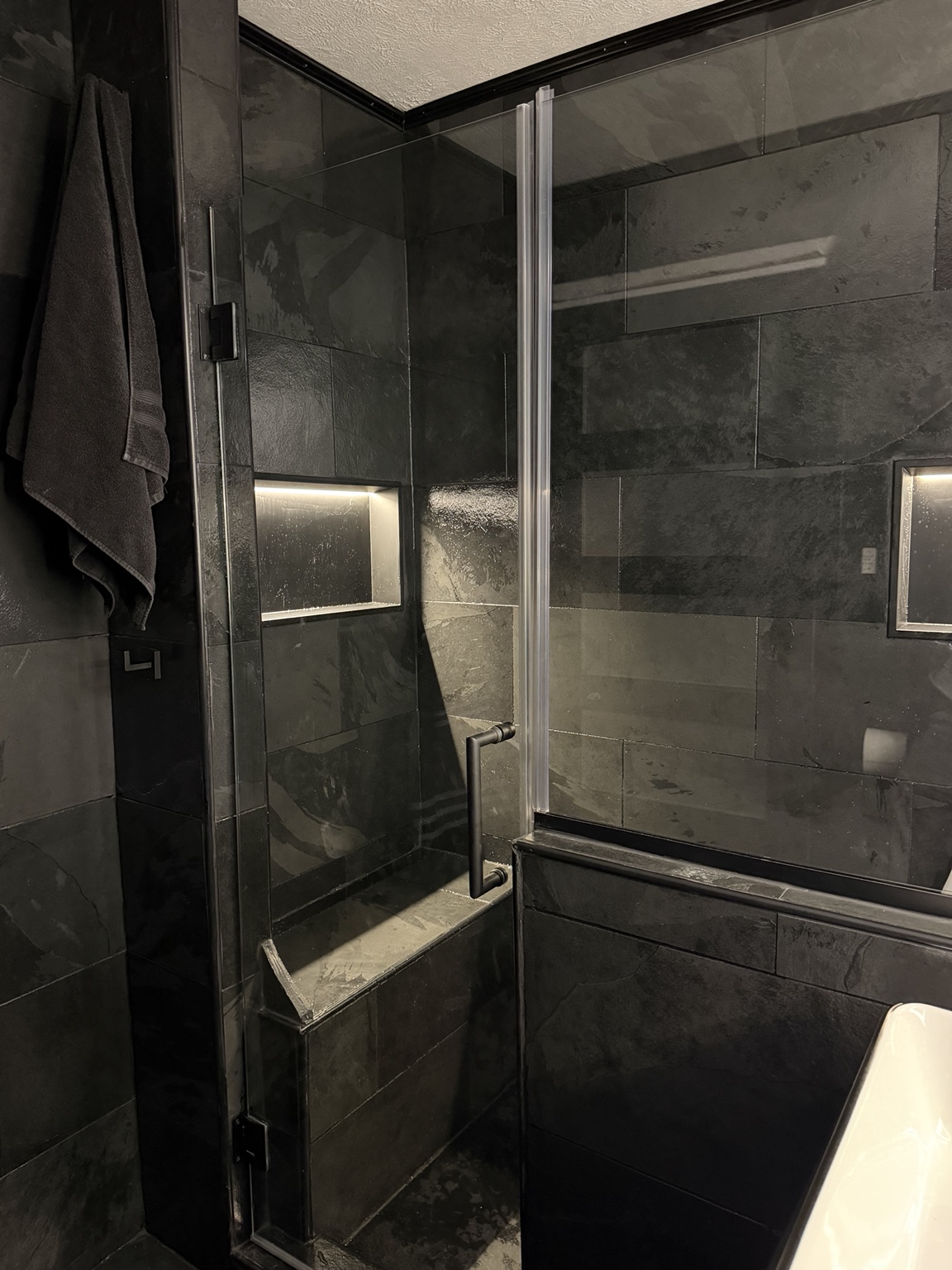 Completed tiled shower with glass door and illuminated wall niches