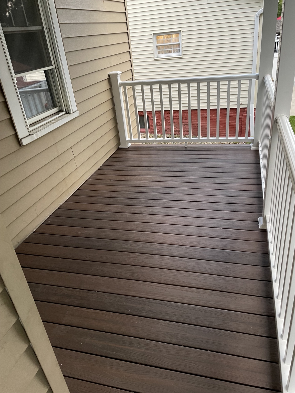 New brown decking with white railing on a covered porch
